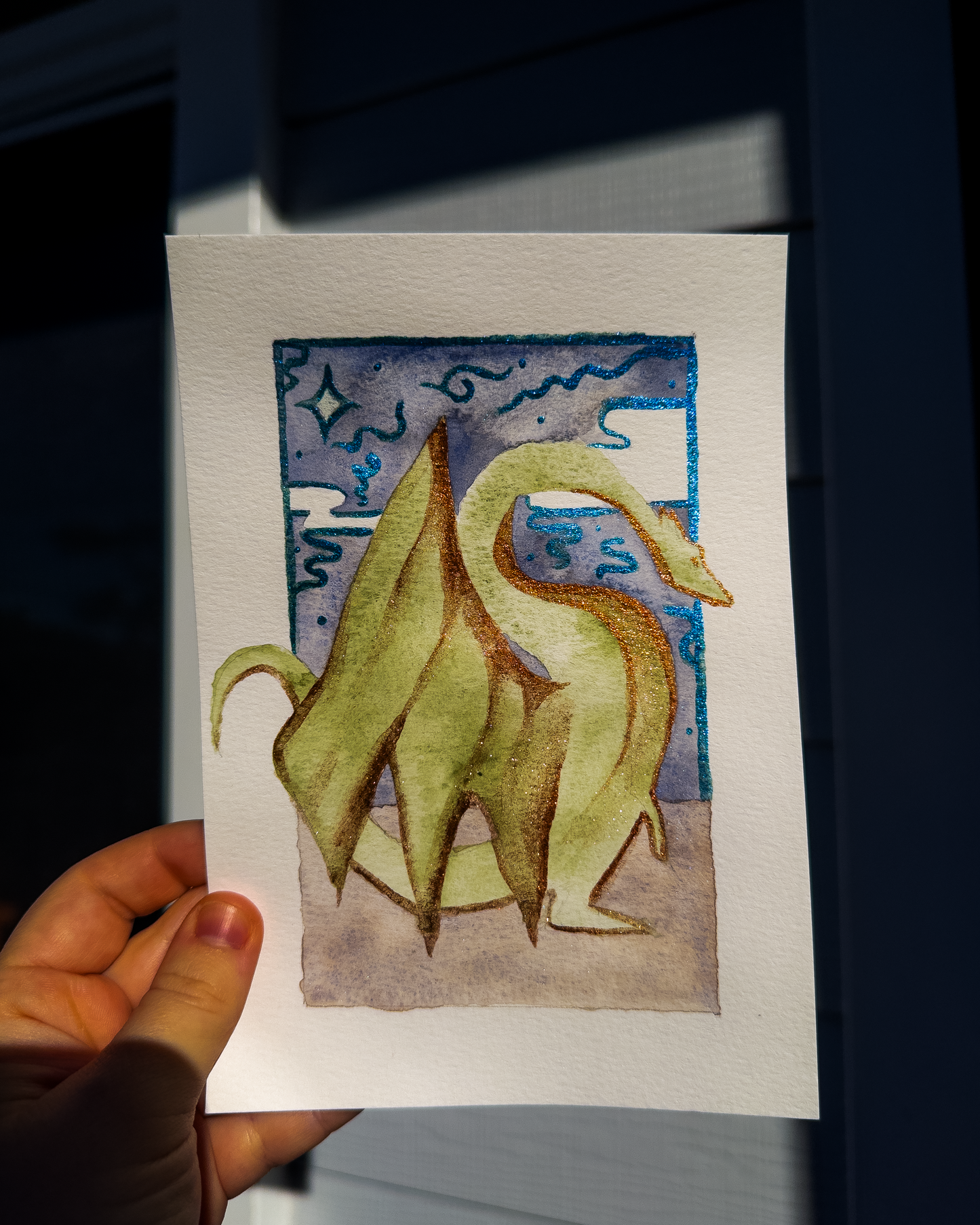 Hand holding a card with a stylized dragon illustration against a dark background