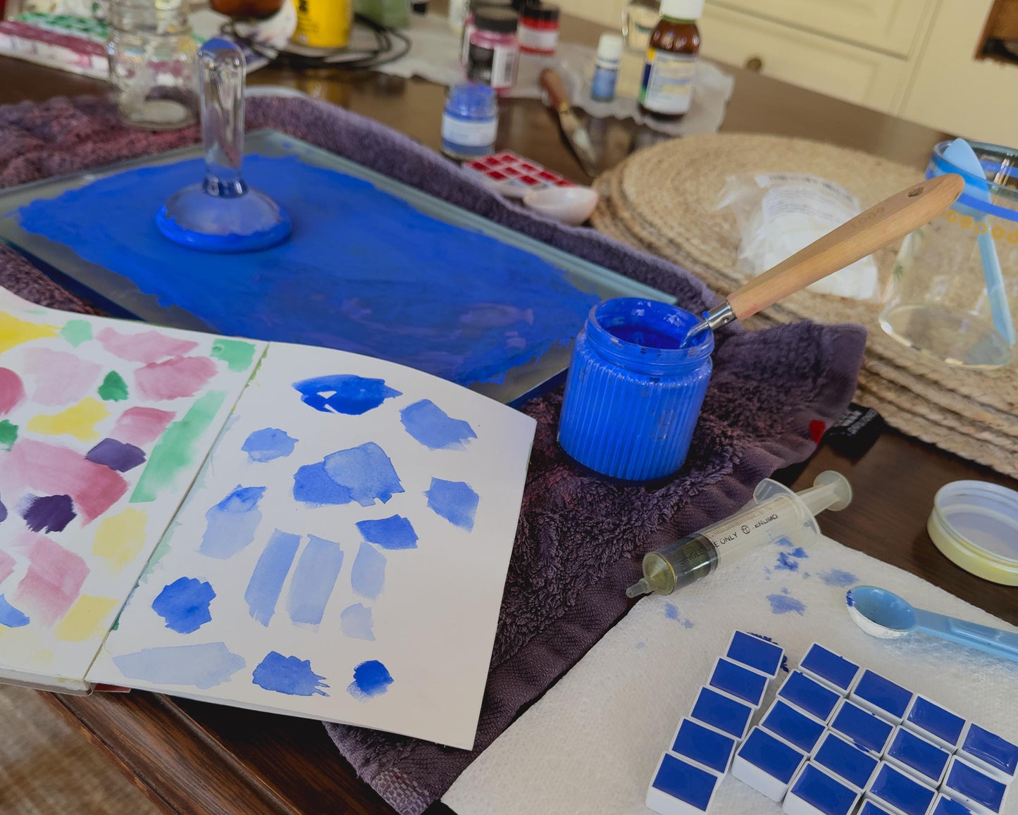 Artistic workspace with watercolor paintings and art supplies on a table.