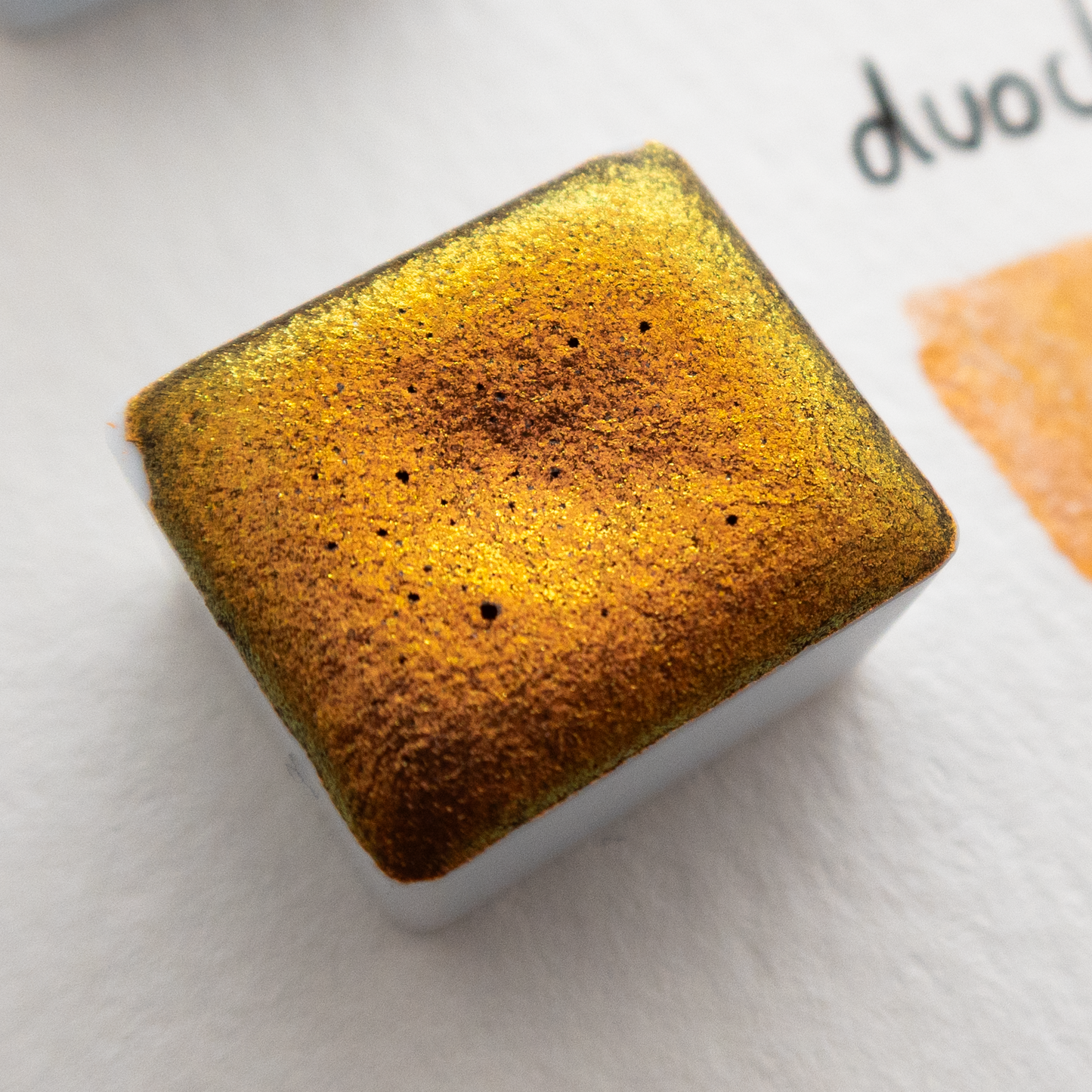 gold watercolour half pan on a white paper background